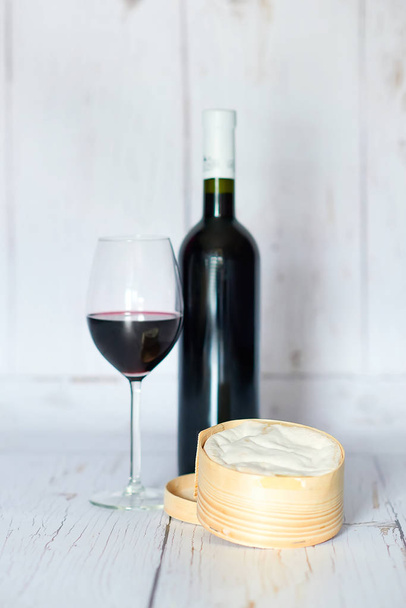 Fles en glas rode wijn en kaas - Foto, afbeelding
