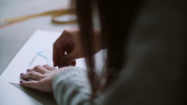 Zadní pohled na mladé ženy mazání na papíře s skica modré boty. Návrhář u stolu a vyvíjet rozložení. 4k - Záběry, video