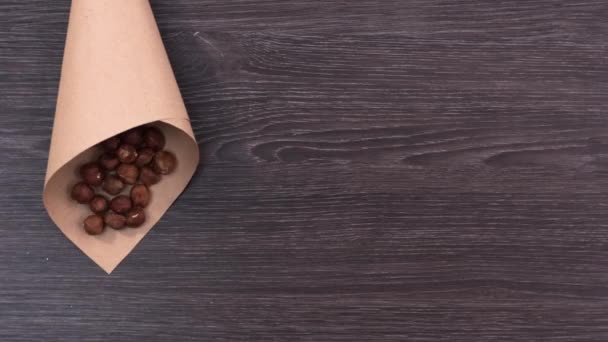 Three paper packages filled with nuts. Filbert, cashew and almonds fall in paper bags near a handful of pine nuts and peanuts. Stop motion - Footage, Video