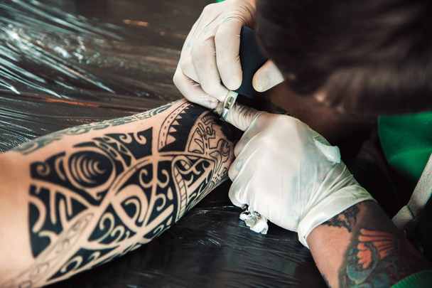 Master tattoo artist in gloves makes tattoo on hand men - Foto, Bild
