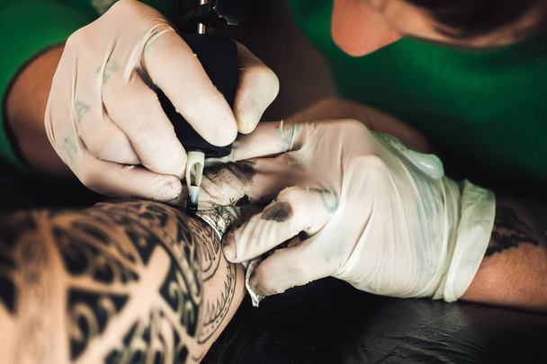 Master tattoo artist in gloves makes tattoo on hand men - Fotó, kép
