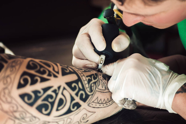 Master tattoo artist in gloves makes tattoo on hand men - Foto, Imagen