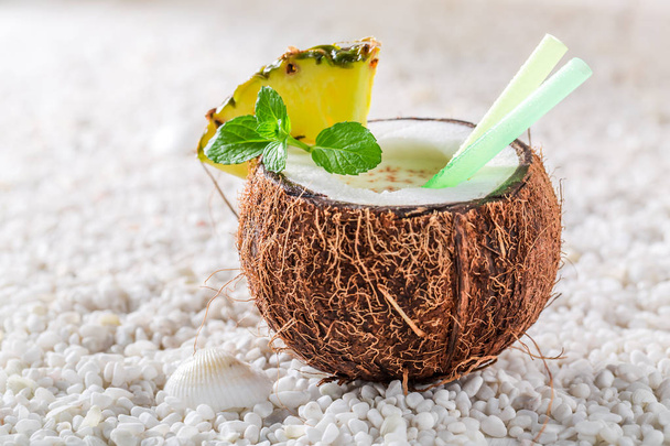Smakelijke pinacolada in kokosnoot met ananas en munt bladeren - Foto, afbeelding