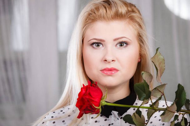 woman holding red rose near face looking melancholic - Photo, image
