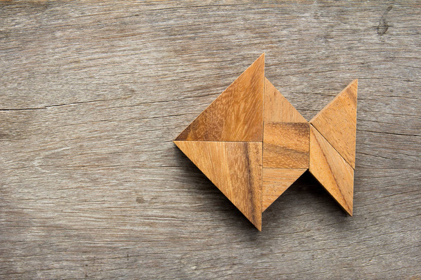 Chinese tangram puzzle in fish shape on wooden background - Photo, Image