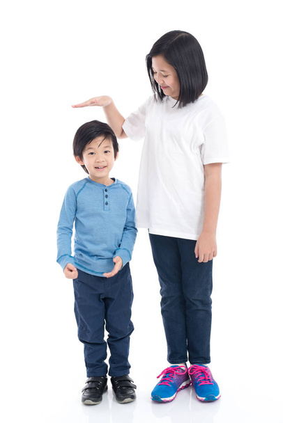 Asiangirl μετρά την αύξηση του αδελφού της σε άσπρο φόντο απομονωμένες - Φωτογραφία, εικόνα