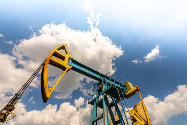 Betrieb von Öl- und Gasbohrungen im europäischen Ölfeld, profiliert am blauen Himmel mit Kumuluswolken, - Foto, Bild
