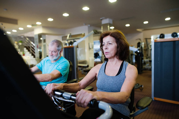 Beautiful fit senior couple in gym doing cardio work out. - Zdjęcie, obraz