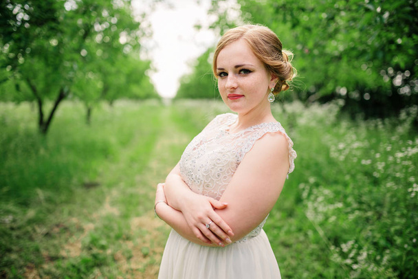 Young overweight girl at beige dress posed background spring gar - Fotó, kép