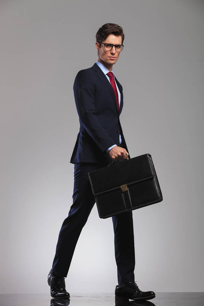 negocios serios sosteniendo un maletín camina hacia adelante con confianza
 - Foto, imagen