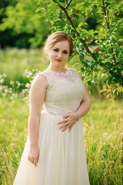 Young overweight girl at beige dress posed background spring gar - Fotografie, Obrázek