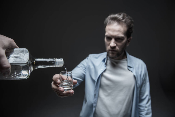 Serious man holding small glass in right hand - Photo, Image