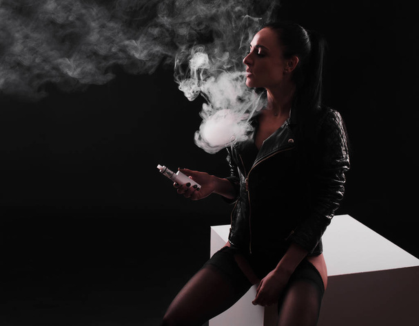 Young beautiful woman smoking ( vaping ) e-cigarette with smoke - Fotó, kép