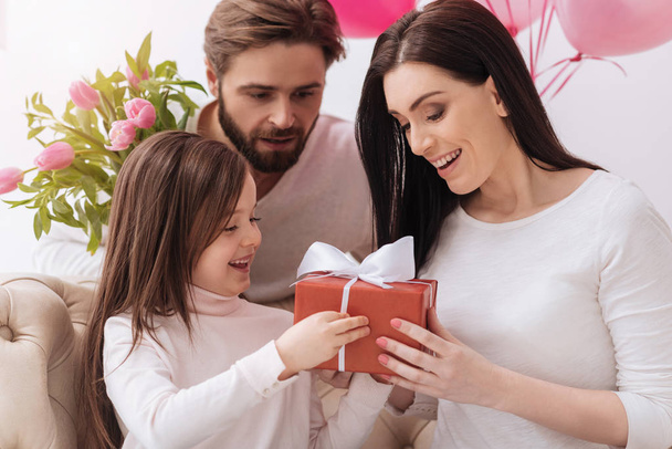 Cute positive mother and daughter holding a gift box - Foto, imagen