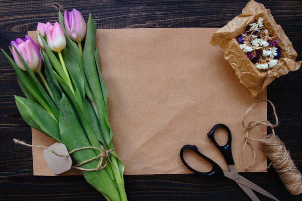 Bouquet of beautiful fresh tulips with accessories on the wooden background. Florist workplace - Foto, Imagen