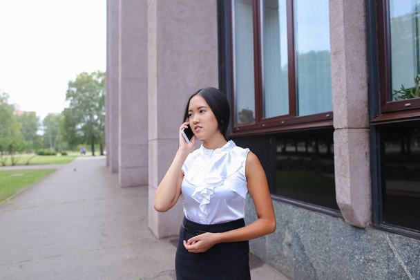 Jonge zakelijke vrouw gesprekken op telefoon en glimlachend op achtergrond van - Foto, afbeelding
