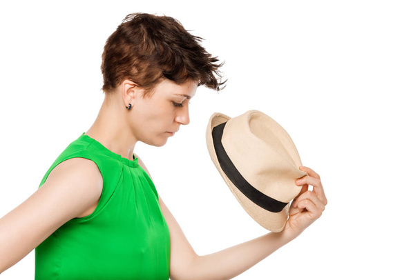 fiatal lány rövid haja gazdaság egy kalap, fehér alapon - Fotó, kép