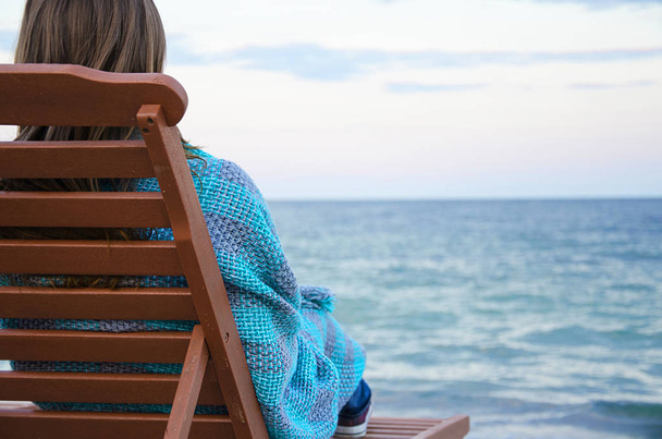 Girl in coverlet on the beach chair on the sea - Photo, Image