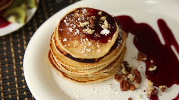 Homemade sweet pancakes with fruit jam, sour cream on a white plate. Breakfast with stack topped blueberry jam and walnuts. - Materiał filmowy, wideo