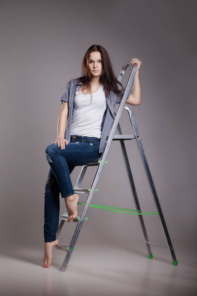 Young woman on step ladder. - 写真・画像