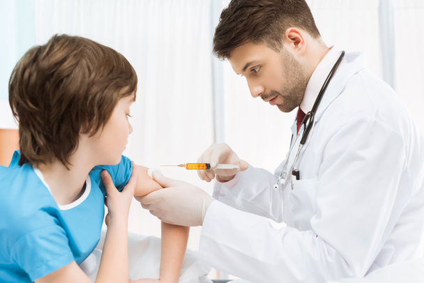 Médico fazendo injeção para menino
 - Foto, Imagem