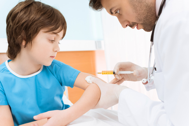 Médico fazendo injeção para menino
 - Foto, Imagem