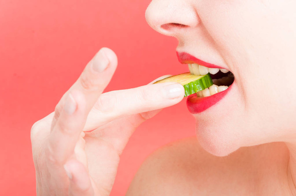 Young woman with slice of cucumber - Zdjęcie, obraz
