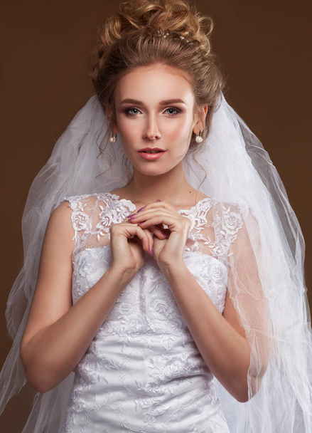 Beautiful elegant bride posing in studio with long veil - Foto, Imagen