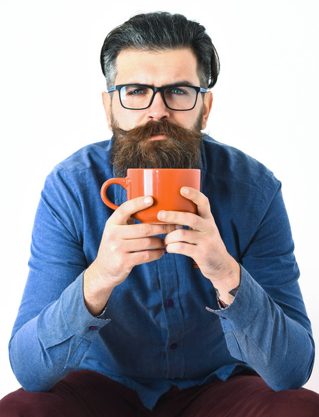 Bearded man, brutal caucasian hipster with moustache holding orange mug - Photo, image