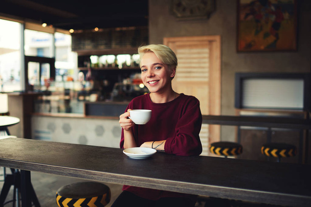 Hipster girl with short haircut drinking hot chocolate for breakfast in morning - Foto, Imagem
