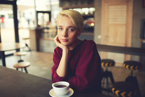 Hipster with natural makeup and trendy short haircut relating with cup of coffee after hard working day - Fotoğraf, Görsel