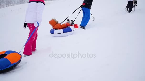 the family rises to snowy hill with snowtube. slow motion. snow winter landscape. Active rest, sports - Footage, Video