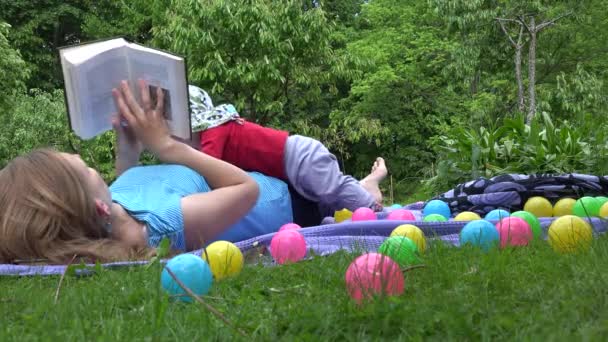Jeune femme après-midi avec livre et bébé dans le jardin. 4K
 - Séquence, vidéo