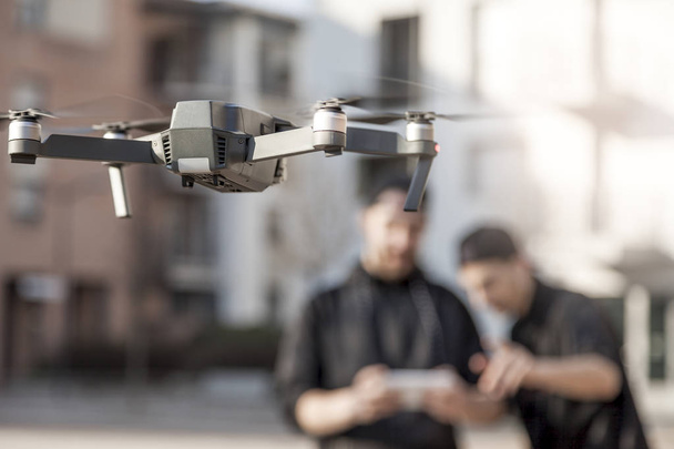 Junge Leute fliegen eine Drohne mit Fernbedienung im Freien - Foto, Bild