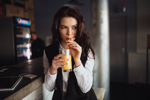 Healthy eating - young woman drinking orange juice at restaurant bar - 写真・画像