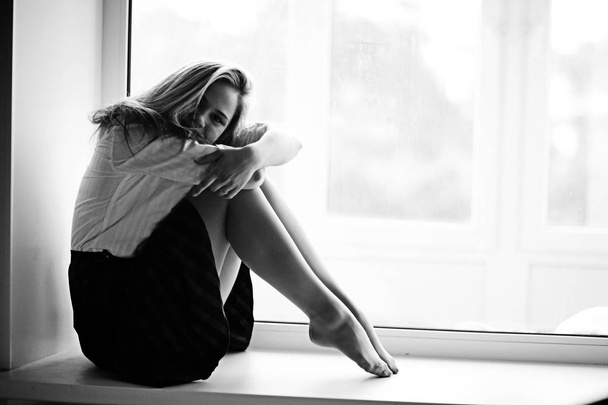 young woman sitting on windowsill - Zdjęcie, obraz