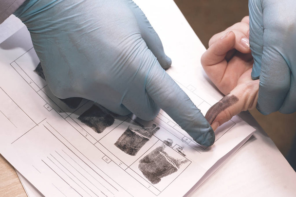 Het onderzoek van de misdaad. De inspecteur neemt vingerafdrukken van een verdachte. - Foto, afbeelding