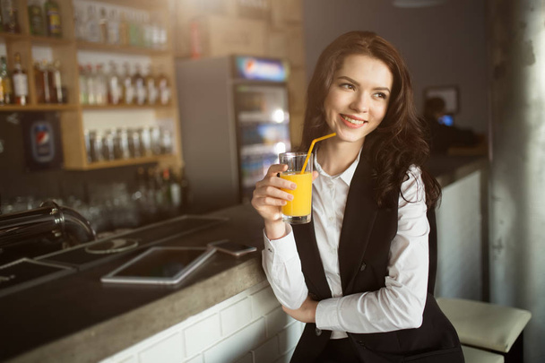 Healthy eating - young woman drinking orange juice at restaurant bar - Фото, изображение