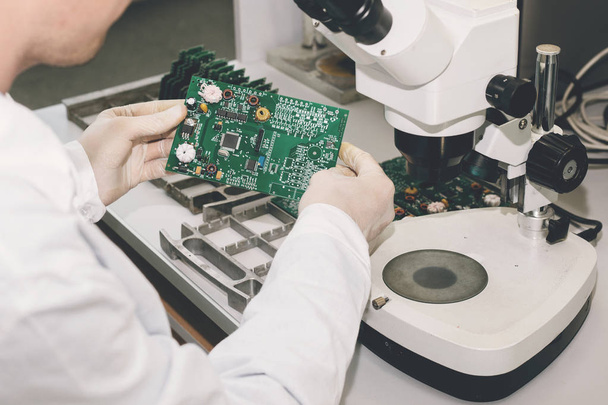 The technician takes a computer board with chips. Spare parts and components for computer equipment. Production of electronics and maintenance. The concept of high technology and robotics. - Foto, Imagem