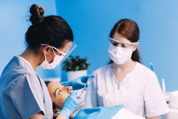 Dentists with a patient during a dental intervention. - Foto, afbeelding