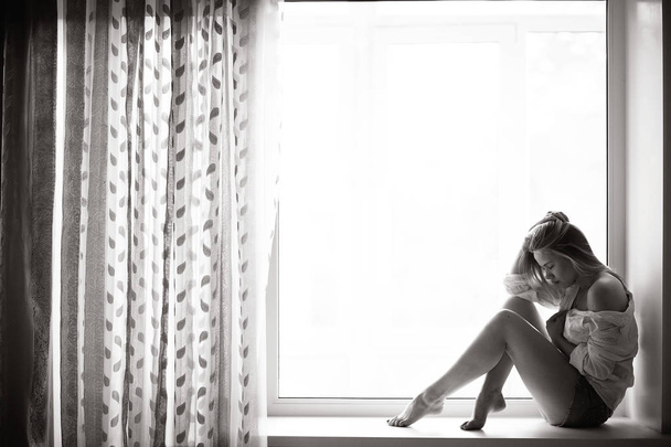 young woman sitting on windowsill - Valokuva, kuva
