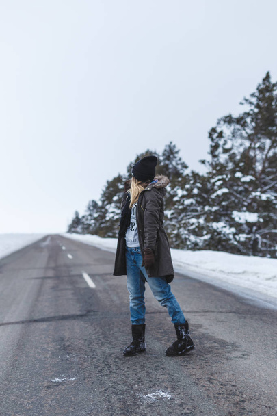 Girl is standing on the winter road - Zdjęcie, obraz