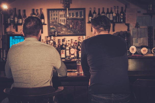Vanhat ystävät juovat luonnos olutta baaritiskillä pubissa
. - Valokuva, kuva
