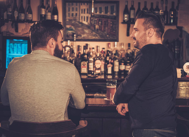 Starzy przyjaciele pić piwo w barze licznika w pubie. - Zdjęcie, obraz
