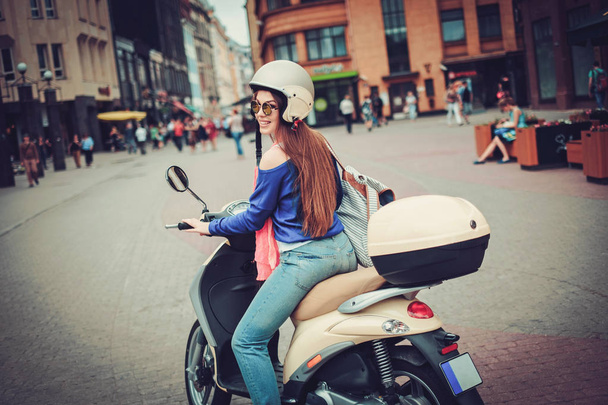 Young cheerful girl near scooter in in european city - Photo, Image
