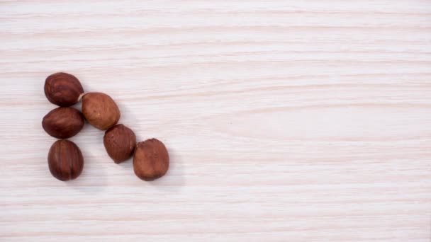The word NUT made from hazelnuts over light wooden background. Stop motion - Filmagem, Vídeo