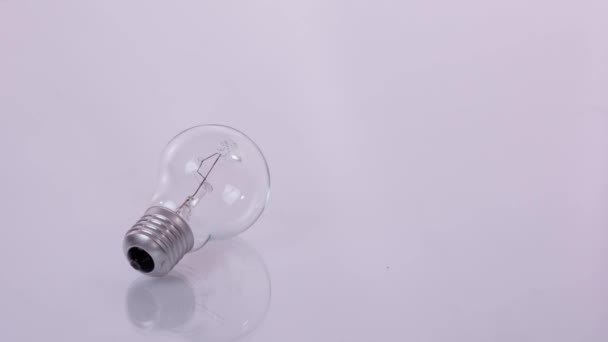 Energiesparen. Energiesparlampen und eine Glühbirne neben einem kleinen und einem großen Stapel Münzen. Stop-Motion - Filmmaterial, Video