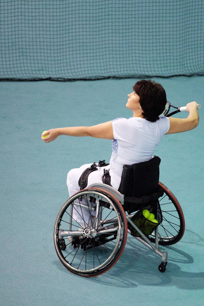 Mujer madura discapacitada en silla de ruedas jugando tenis en pista de tenis
. - Foto, imagen