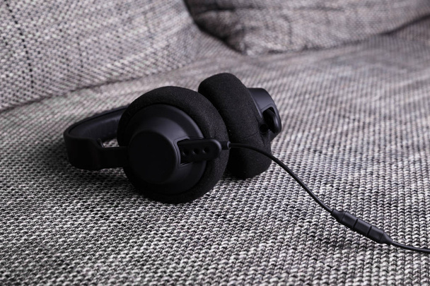 Headphones lying on sofa. Musical concept. - 写真・画像