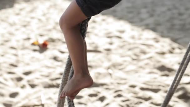 Roztomilá holčička hraje a dělá gymnastické cvičení na houpačce na písečné pláži - Záběry, video